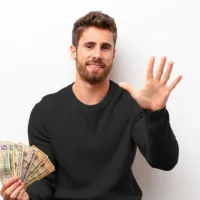 Business owner holds up 5 fingers of one hand while holding a stack of money in the other