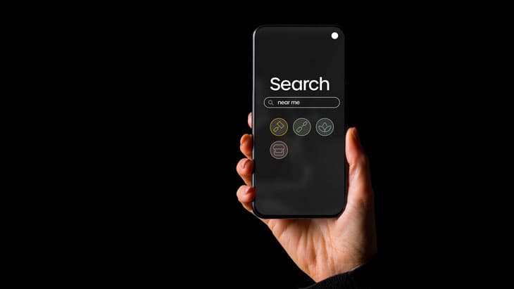 An upheld smartphone shows a search engine screen with 