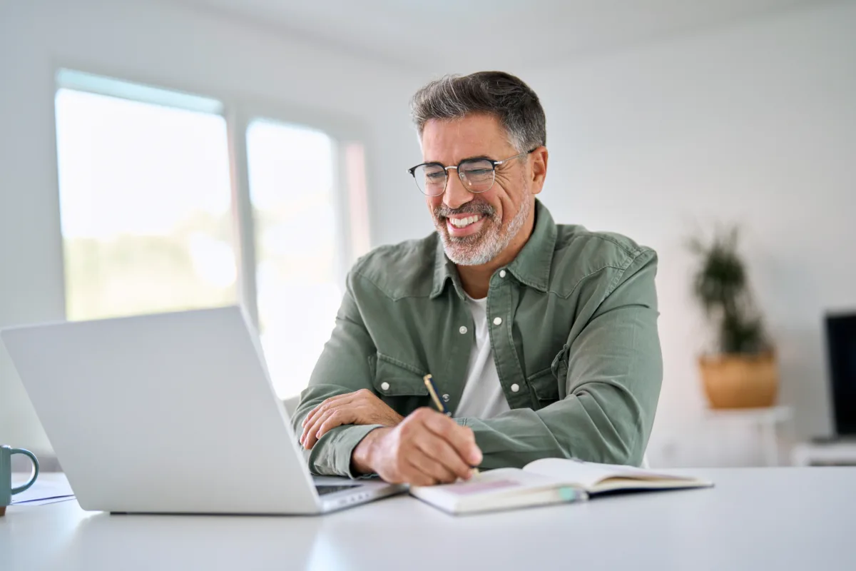 A smiling business owner looks at website business growth on their laptop.