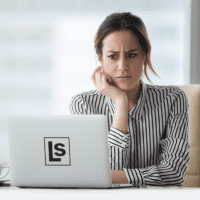 Local Business Owner stares critically at her website on a laptop, trying to decide if it needs improvement